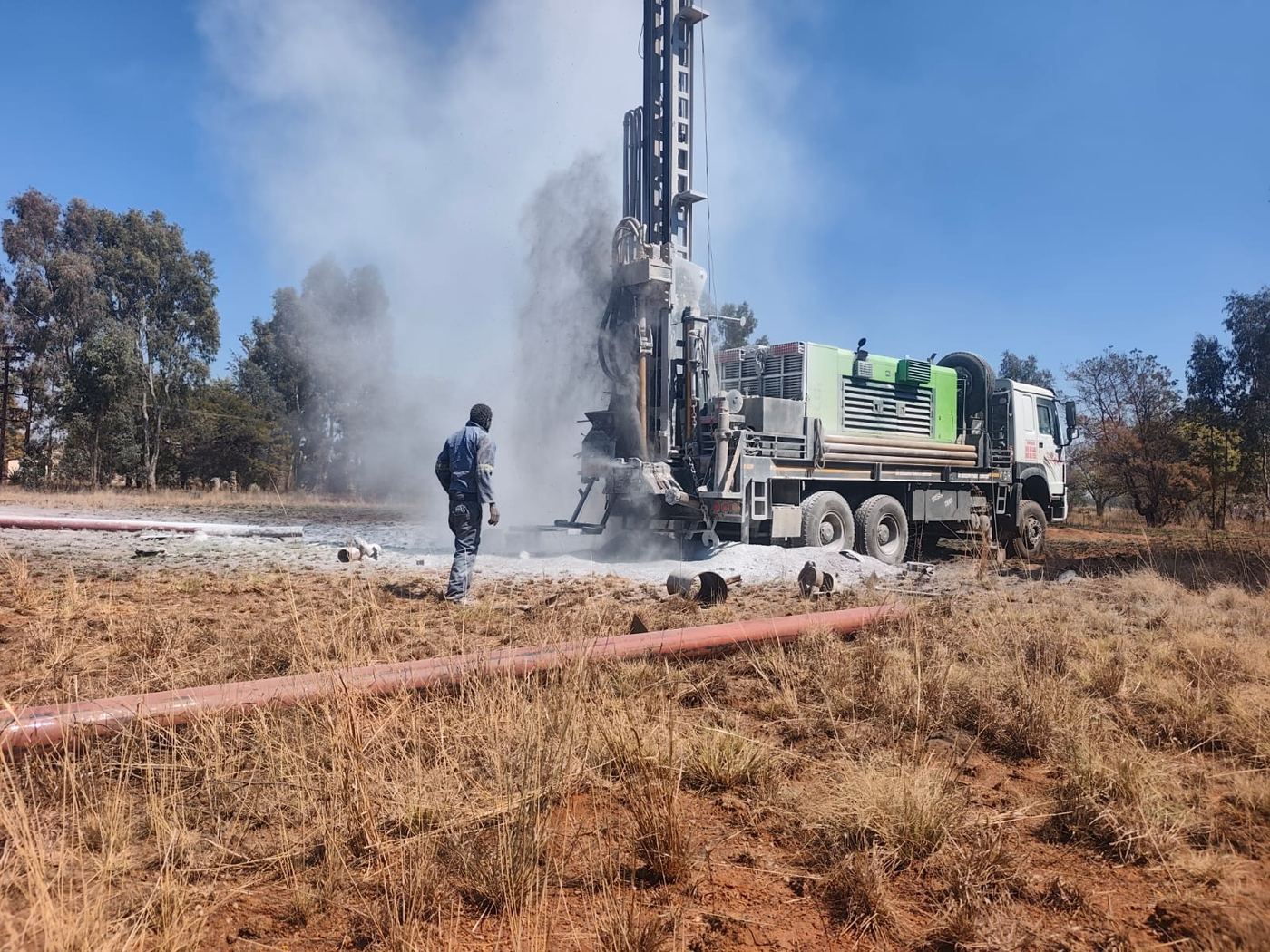 Borehole drilling rig at work under a clear sky