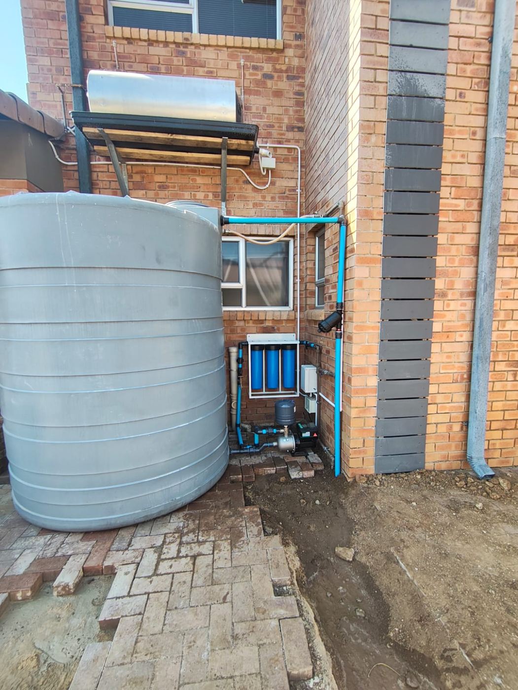 Large tank with pressure pump against a brick wall